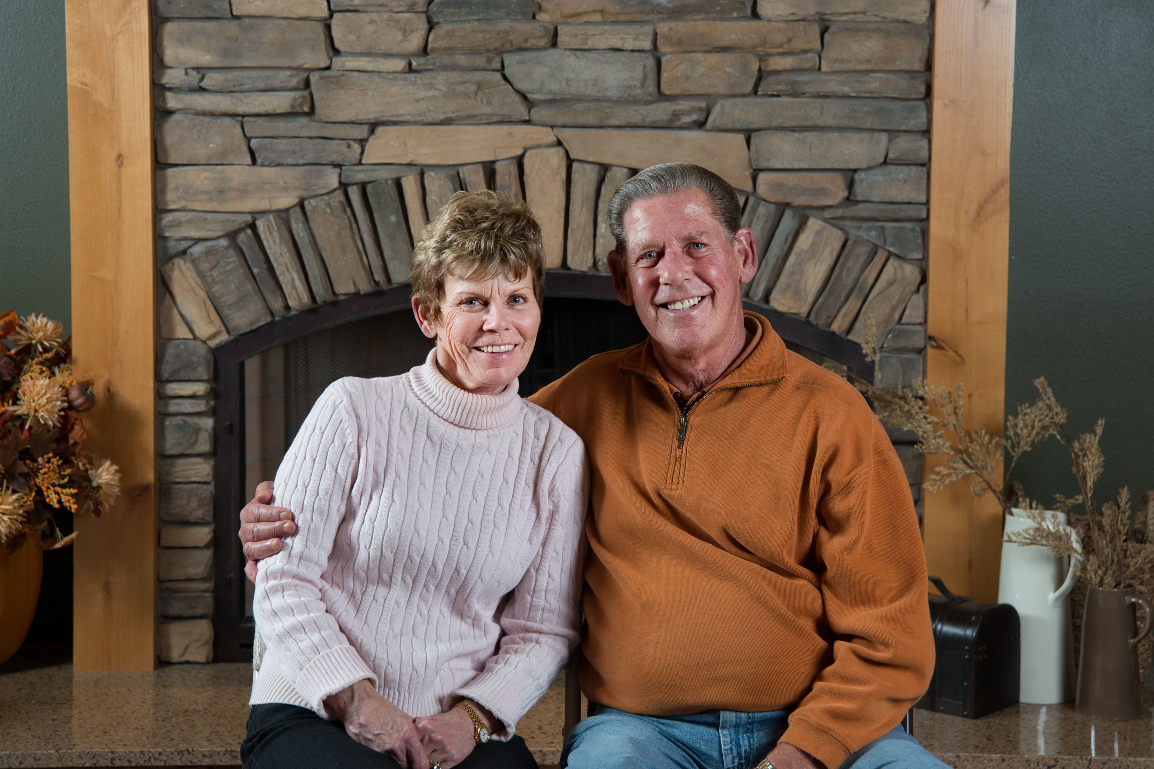 Ron and Georgia Lee Puryear smiling together near a stone fireplace